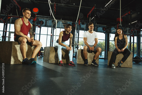 A group of muscular athletes doing workout at the gym. Gymnastics, training, fitness workout flexibility. Active and healthy lifestyle, youth, bodybuilding. Training with sportive jump boxes.