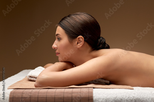 wellness, beauty and relaxation concept - young woman lying at spa or massage parlor