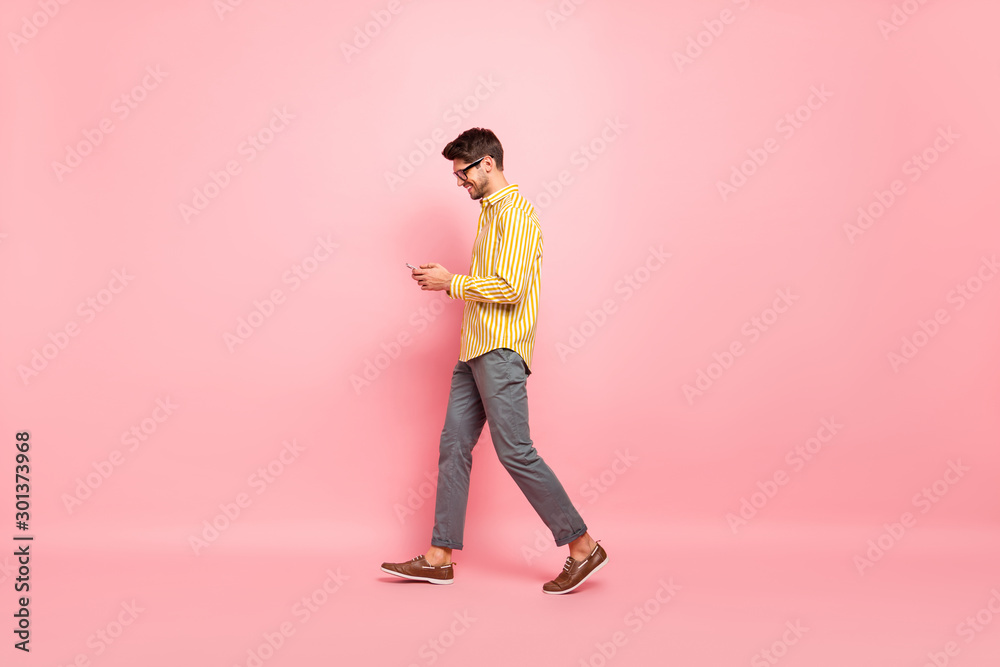 Full size profile photo of handsome guy going street finished working week typing girlfriend sms telephone wear specs striped shirt pants isolated pink color background - obrazy, fototapety, plakaty 
