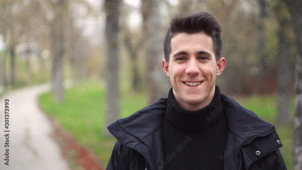 Portrait of happy young man smiling and laughing on camera in the park . Portrait of happy young man smiling and laughing on camera in the park .