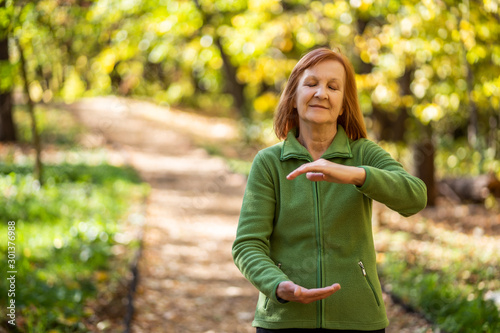 Quadro su tela Senior woman is practicing Tai Chi exercise in park.
