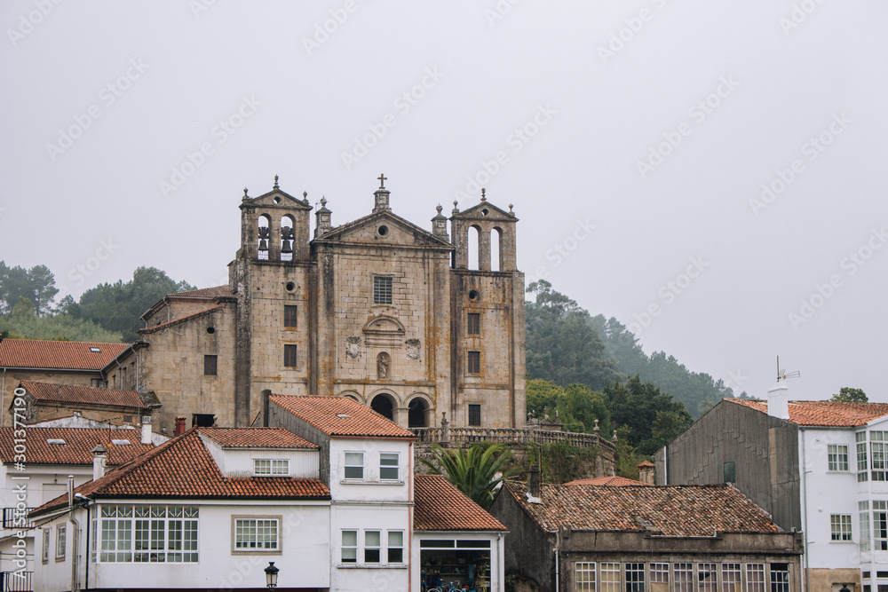Padron, Spain - 10/20/2018: landmark od Padron in Galicia, Spain. Ancient temple with houses on Camino de Santiago way. Medieval catholic architecture. Travel in Europe.