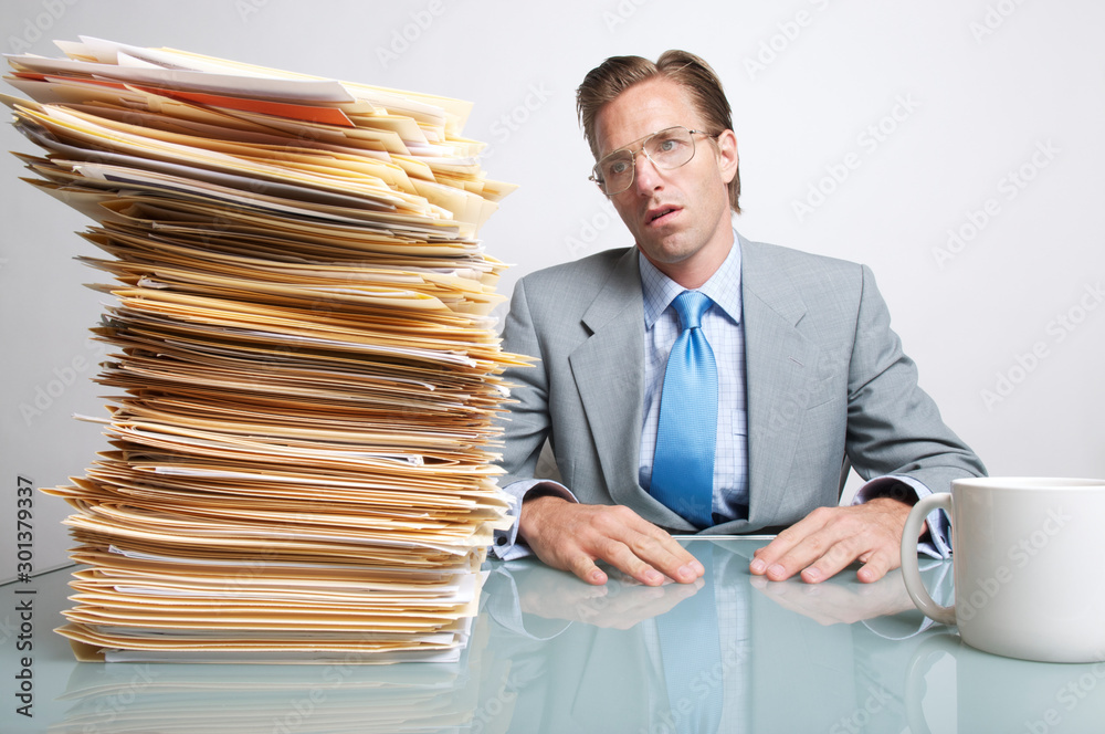 Φωτογραφία Businessman looking overwhelmed by the stack of paperwork on his desk