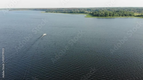 Motorboat at high speed moving to the shore in Sunny clear weather. Big deep lake with motorboat. The camera follows the motorboat photo