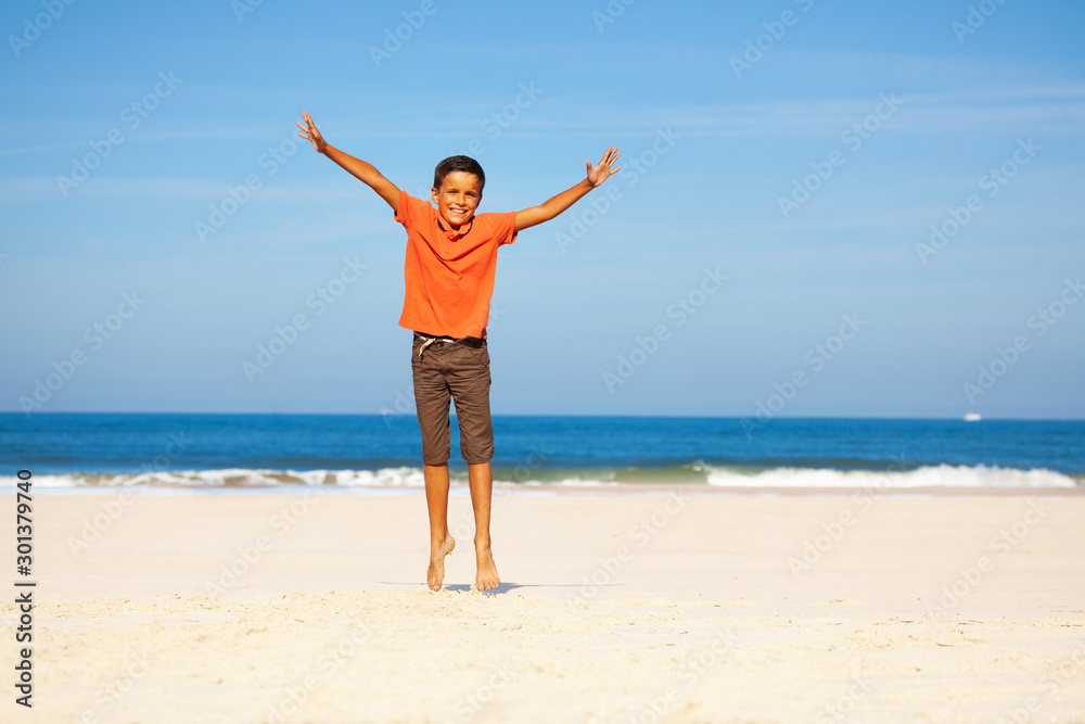 Happy boy jump up with spread hands over sea beach Happy boy jump up with spread hands over sea beach