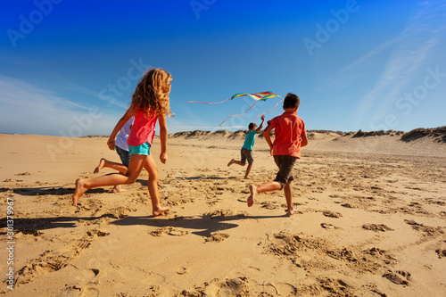 Group of kids run away with color kite on a beach