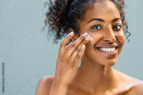 Woman applying moisturizer on face photo