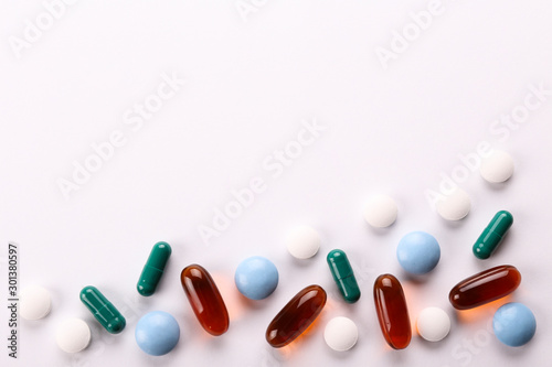 Flat lay composition with bunch of different colorful pills in scattered all over the table. Pile of opened medication on paper textured background. Close up  copy space.