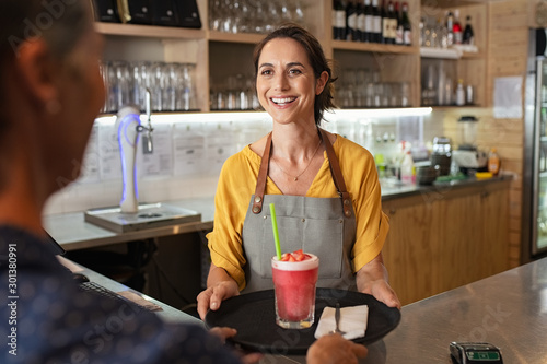 Foto Smiling waitress serving strawberry smoothie