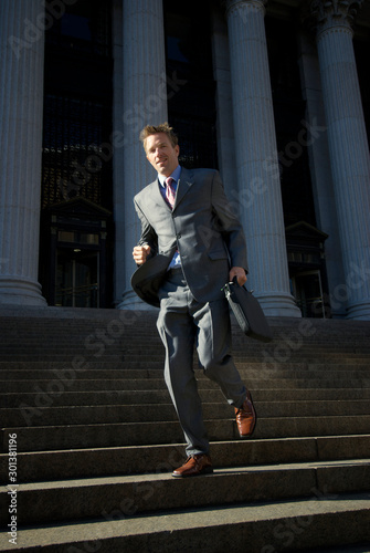 Confident lawyer businessman running down dark steps with grand courthouse columns in the background