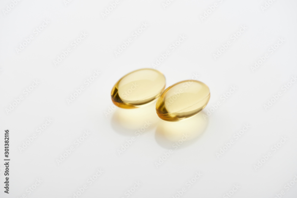 two golden fish oil capsules on white background two golden fish oil capsules on white background