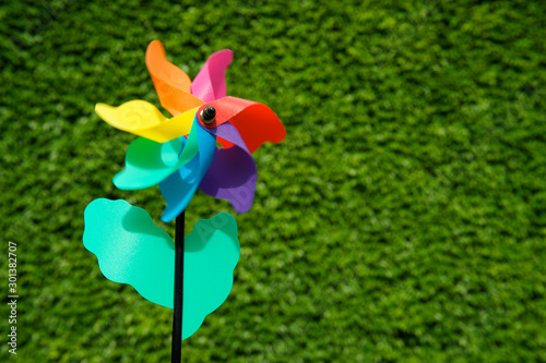 Colorful pinwheel flower spinning in the wind in front of a natural green background 