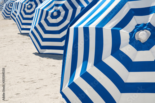 Classic blue and white striped beach umbrellas lined up along the sand on Miami Beach, Florida photo