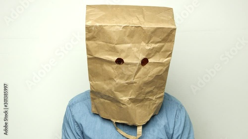 paranoid man has a bag on his head and looks into the camera. Shot on RED.