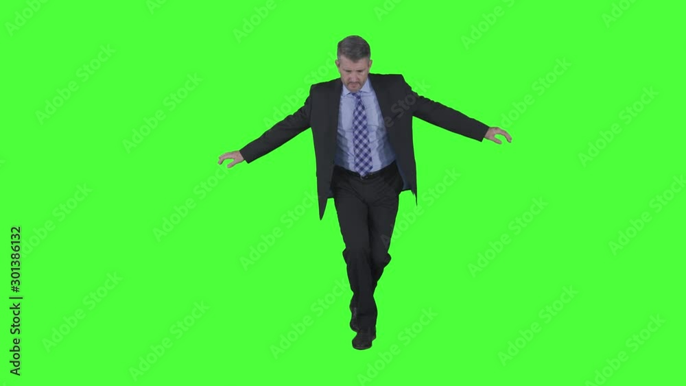 Caucasian businessman walking while keep his balancing on the floor in the studio. Shot in 4k resolution with green screen background Caucasian businessman walking while keep his balancing on the floor in the studio. Shot in 4k resolution with green screen background