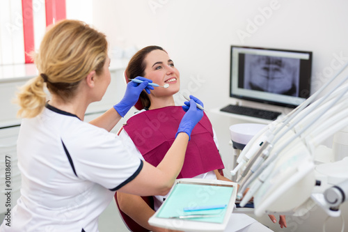 dentist working with happy female patient at dental clinic