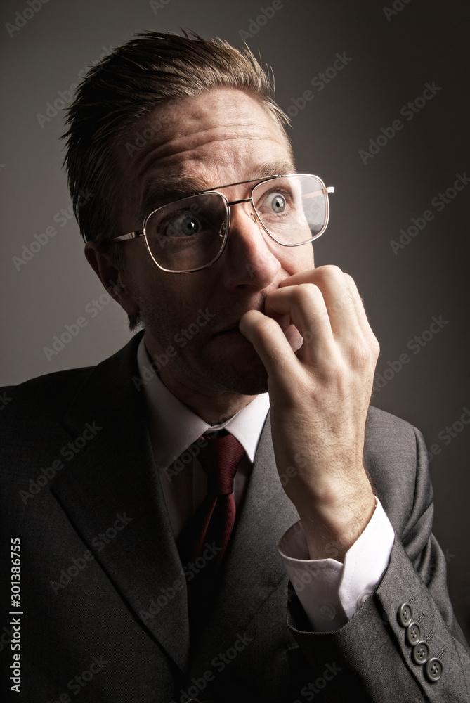 Stressed businessman biting his fingernails with a nervous expression Stressed businessman biting his fingernails with a nervous expression