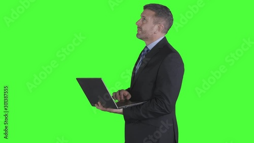 Wallpaper Mural Caucasian businessman working with a laptop while thinking and standing in the studio. Shot in 4k resolution with green screen background Torontodigital.ca