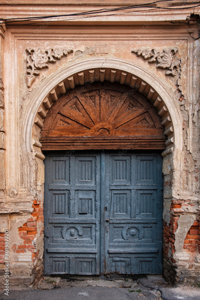 Old arched wooden door in ornate wall