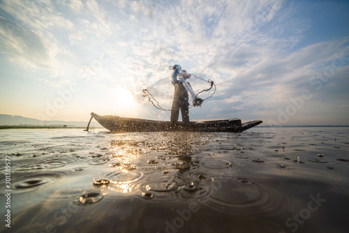 Fototapet Picture of Asian fishermen on a wooden boat Thai fishermen catch fresh water fis