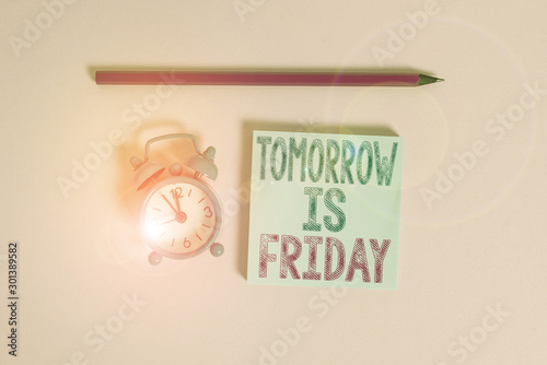 Word writing text Tomorrow Is Friday. Business photo showcasing Weekend Happy holiday taking rest Vacation New week Metal vintage alarm clock wakeup blank notepad marker colored background