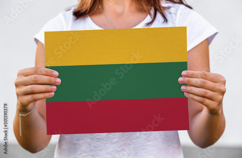 woman holds flag of Lithuania on paper sheet