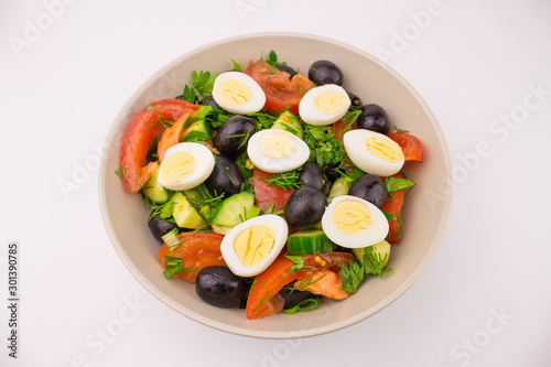 Salad with quail eggs tomato cucumber olive greens. Mix of fresh vegetables, Mediterranean cuisine. Plate with egg and vegetable salad