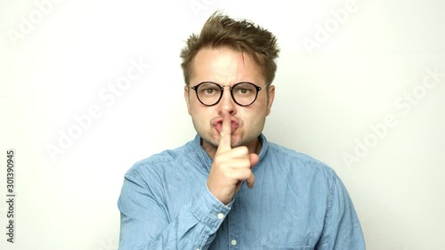 Angry funny guy showing .silence gesture to the camera. Shot on RED.