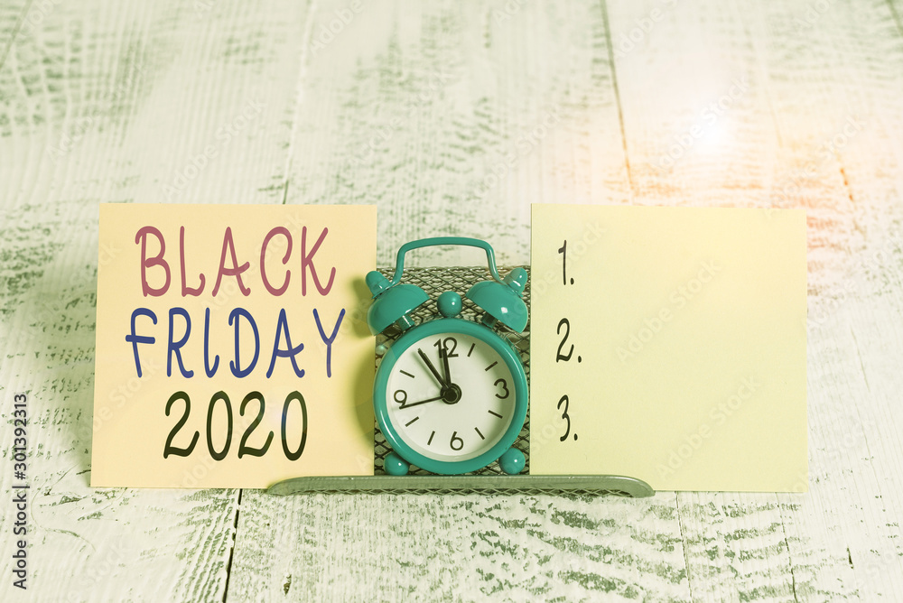 Writing note showing Black Friday 2020. Business concept for day following Thanksgiving Discounts Shopping day Mini blue alarm clock standing above buffer wire between two paper