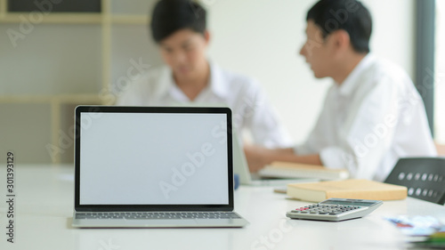 White blank screen tablet on office desk and staff behind.