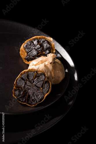 Black garlic on black plate. photo