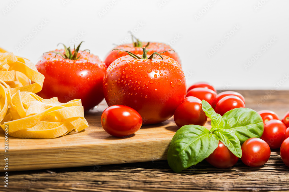 TOMATOES ON A BOARD WITH BASIL AND SPICES TOMATOES ON A BOARD WITH BASIL AND SPICES