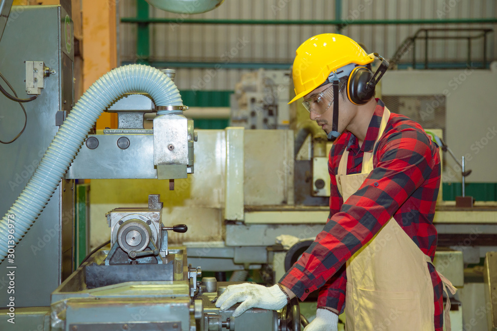 Worker in protective clothing in factory using machine
