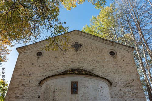 Eastern stone wall of church situated in village Gela, in the hearth of the Rhodope Mountains, Bulgaria. Colorful autumn landscape and a blue sky. photo