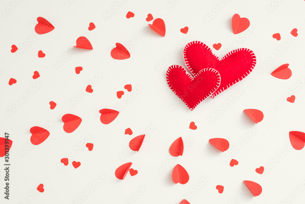 Saint Valentine day. Two red handmade felt hearts on love pattern white background.