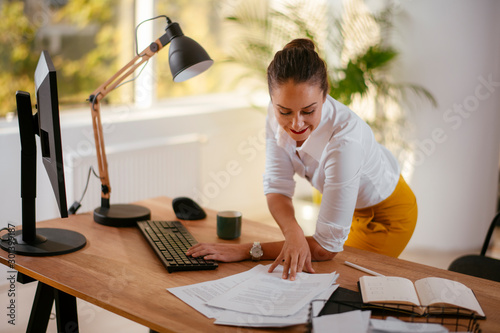Businesswoman in office. Beautiful young woman working on paperwork at her workplace.