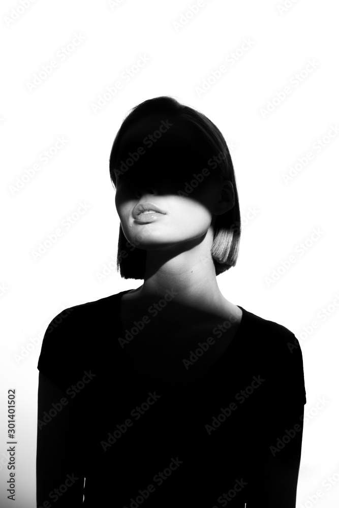 Fashionable beauty portrait. Black silhouette on white background. Girl with a spot of light on her face. 