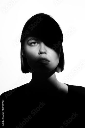 Fashionable beauty portrait. Black silhouette on white background. Girl with a spot of light on her face. 