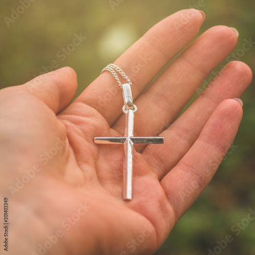 Woman holding a the cross in hand. concept for faith, spirituality and religion.