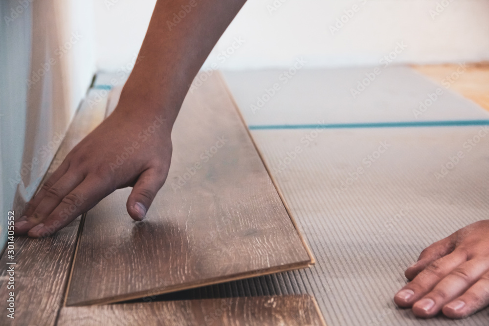 The hands in the work. Construction of laminate floor The hands in the work. Construction of laminate floor