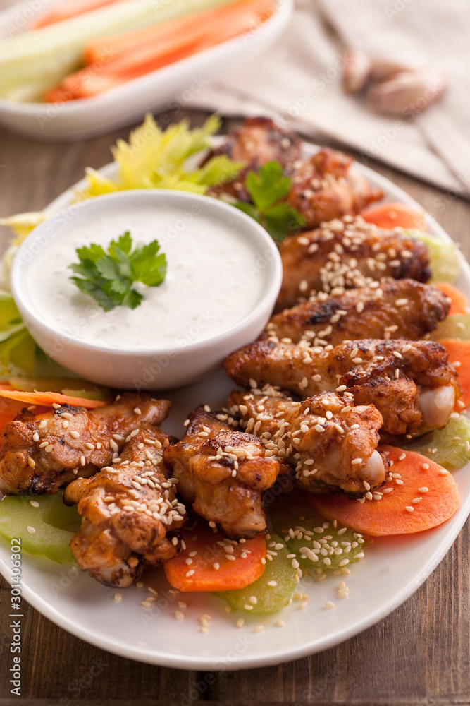 Hot buffalo chicken wings with blue cheese sauce and fresh vegetables.