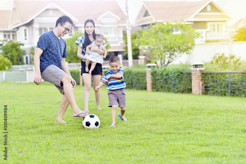 Portrait of Asian family playing football together in garden Portrait of Asian family playing football together in garden