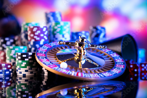Casino theme. Gambling games. Roulette, dice and poker chips on a colorful bokeh background.
