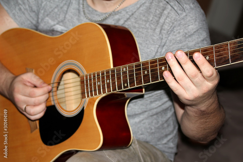 man plays a six-stringed wooden guitar, musical concept, close-up
