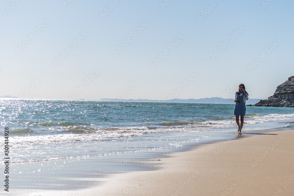 Young lady in blue dress enjoying the beach at a sunny afternoon