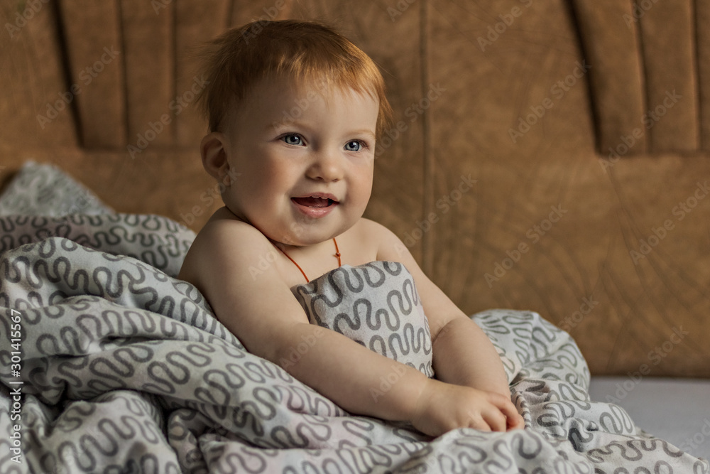 Little red-haired child sitting wrapped in a blanket. Lifestyle. Little red-haired child sitting wrapped in a blanket. Lifestyle.