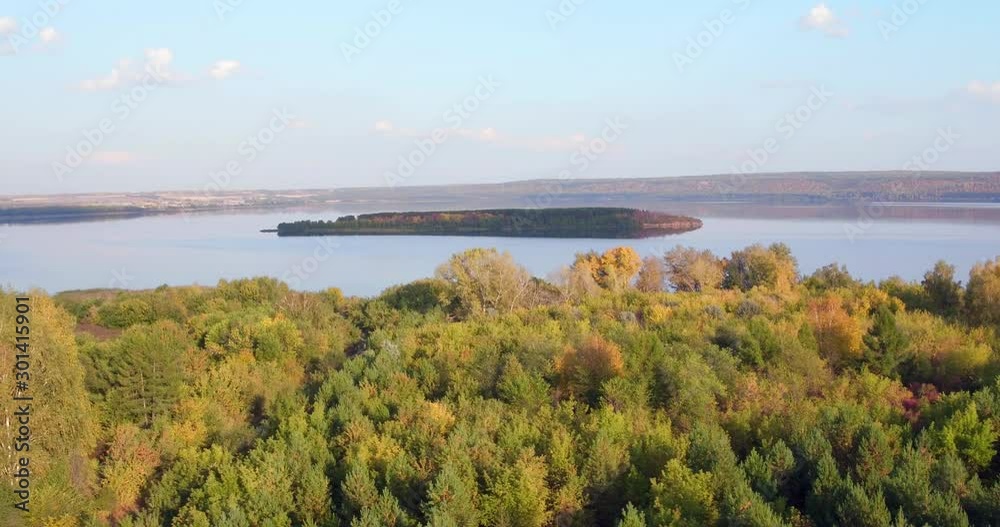 Alone forest island in center large lake at autumn sunny sunset / Aerial drone view Alone forest island in center large lake at autumn sunny sunset / Aerial drone view