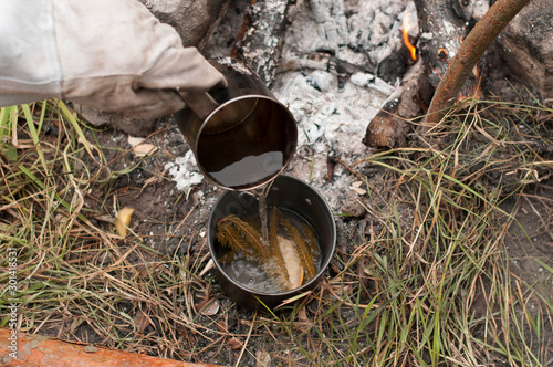 Aromatic and hot herbal tea on campfire 