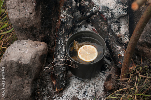 Aromatic and hot herbal tea on campfire 