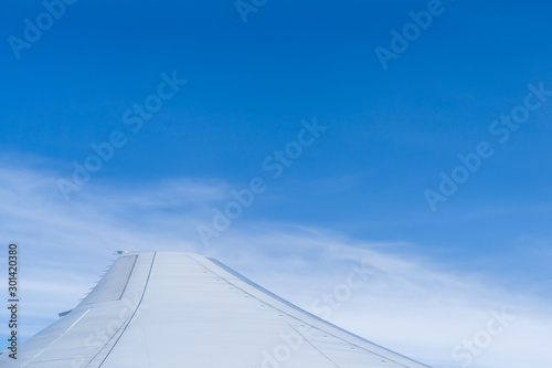 Airplane wing with sky and clouds background